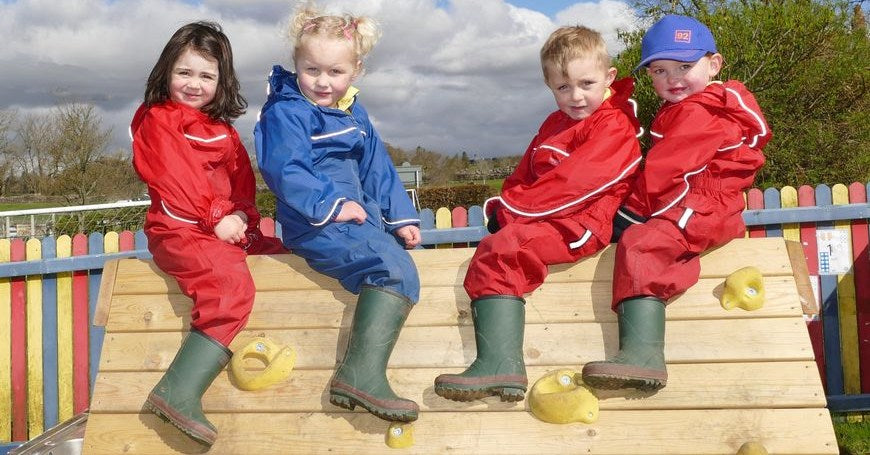 School children sitting on climbing frame wearing Warm Wellies